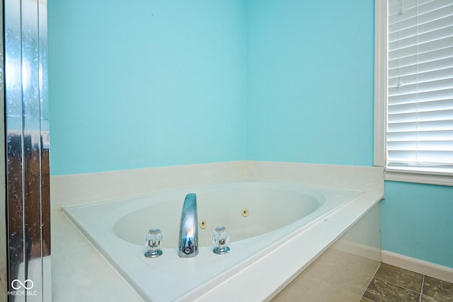 bathroom with a tub with jets and baseboards