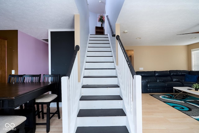 staircase with a textured ceiling and wood finished floors