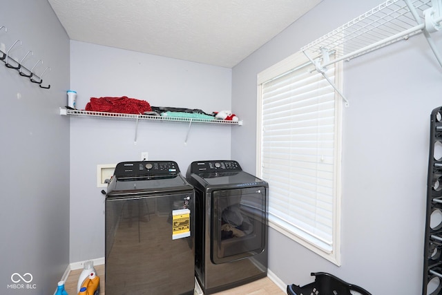 laundry area featuring laundry area, plenty of natural light, washing machine and clothes dryer, and baseboards