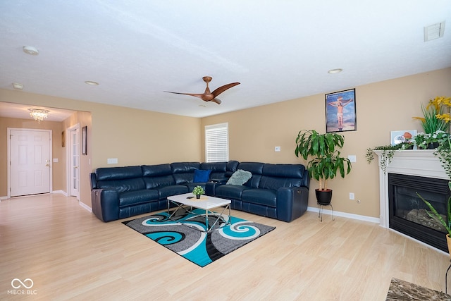 living room with baseboards, visible vents, a glass covered fireplace, ceiling fan, and wood finished floors