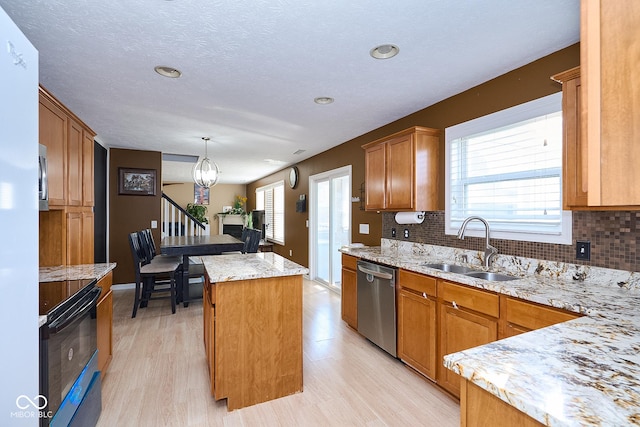 kitchen with decorative backsplash, a kitchen island, a healthy amount of sunlight, stainless steel dishwasher, and a sink