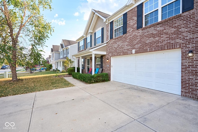 view of front of home featuring an attached garage, a residential view, concrete driveway, and brick siding