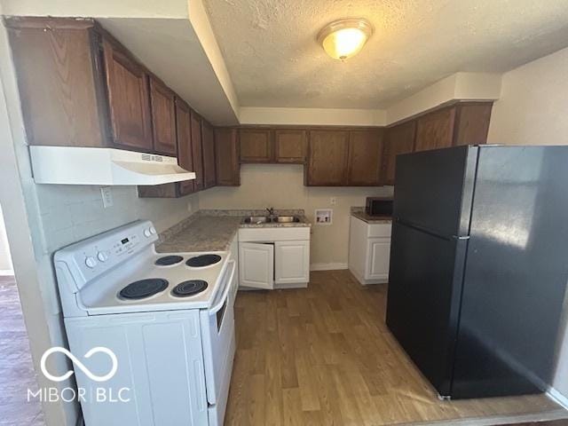 kitchen with electric range, wood finished floors, freestanding refrigerator, under cabinet range hood, and a sink