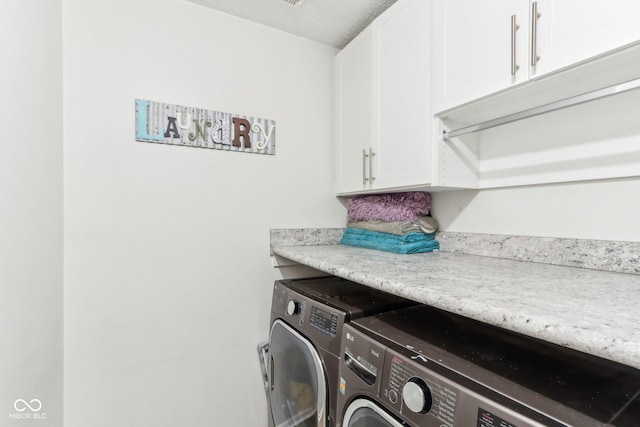 clothes washing area with washing machine and dryer and cabinet space