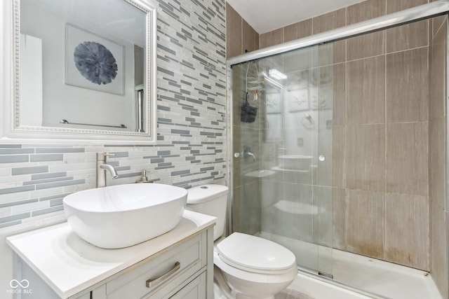 bathroom featuring toilet, vanity, tile walls, backsplash, and a shower stall