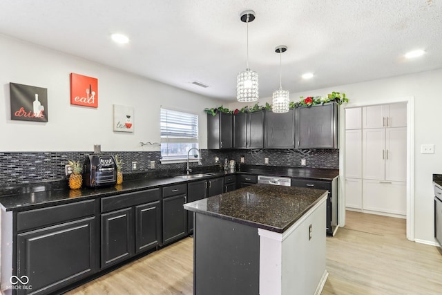 kitchen with dishwasher, decorative backsplash, a sink, and light wood-style floors