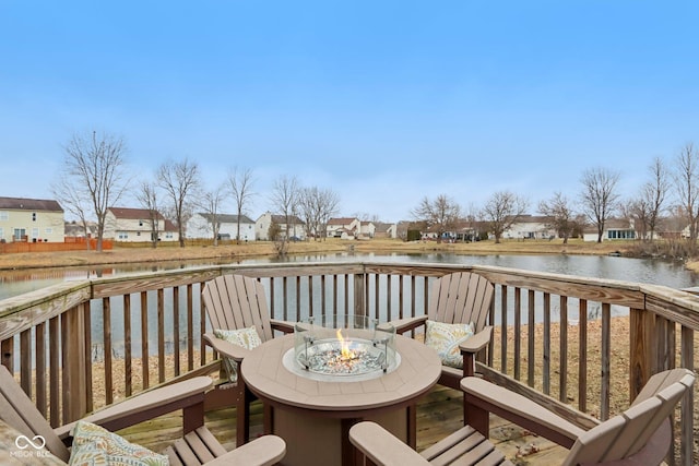 wooden terrace with a residential view, a water view, and a fire pit