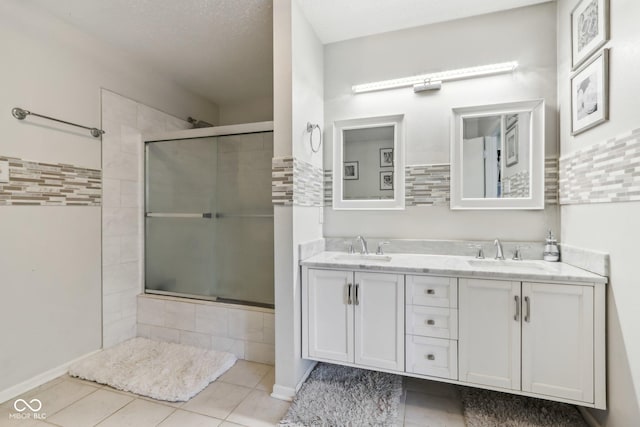 full bathroom featuring a sink, a tile shower, and double vanity