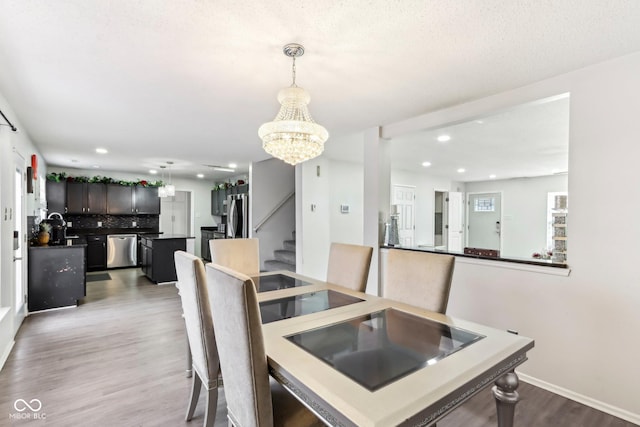 dining room with baseboards, wood finished floors, an inviting chandelier, stairs, and recessed lighting