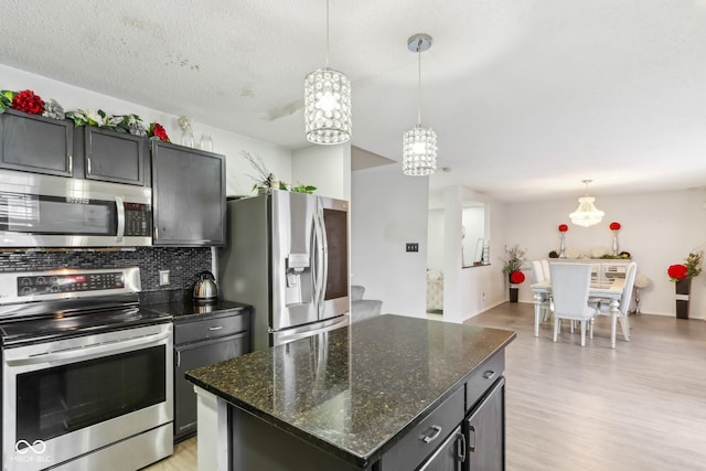 kitchen featuring stainless steel appliances, a kitchen island, light wood-type flooring, tasteful backsplash, and pendant lighting