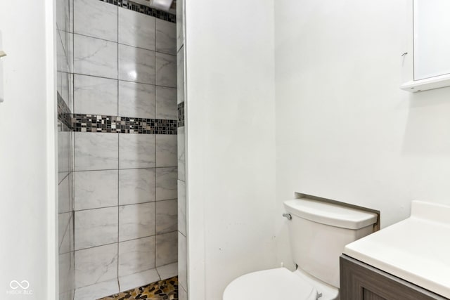 full bath with toilet, tiled shower, and vanity