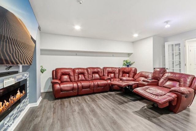 living room with a warm lit fireplace, recessed lighting, wood finished floors, and baseboards