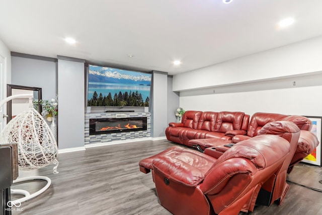 living room featuring a glass covered fireplace, baseboards, recessed lighting, and wood finished floors