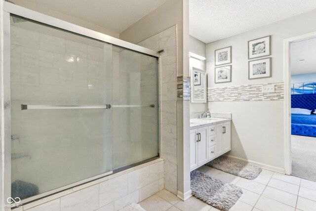 ensuite bathroom with tile patterned floors, baseboards, tiled shower, and vanity