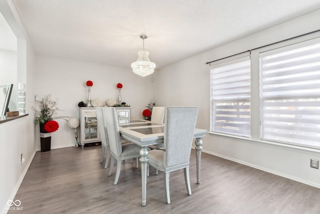 dining room featuring baseboards, light wood-type flooring, and an inviting chandelier