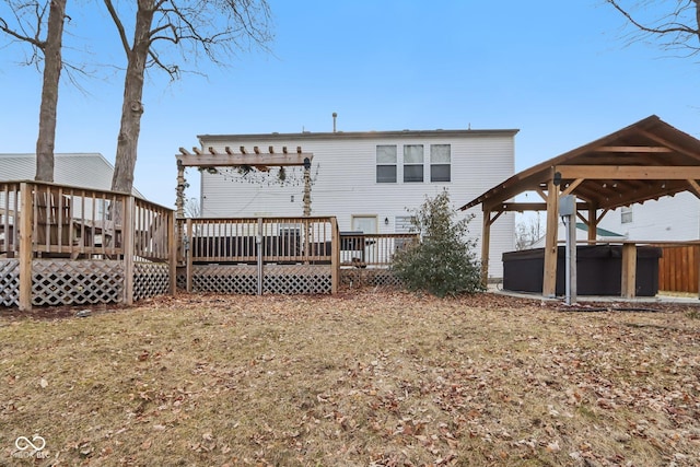 rear view of house with a gazebo, a pergola, a wooden deck, and a hot tub