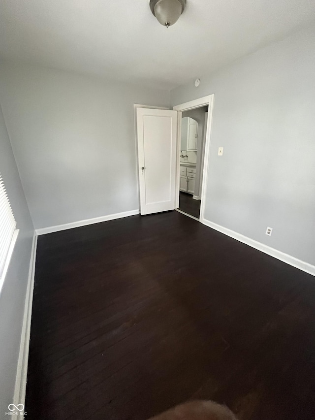 empty room with dark wood-style floors and baseboards