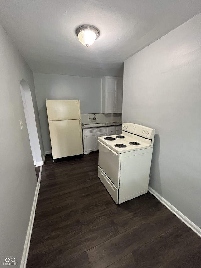 kitchen featuring white appliances, baseboards, arched walkways, dark wood-style flooring, and white cabinetry