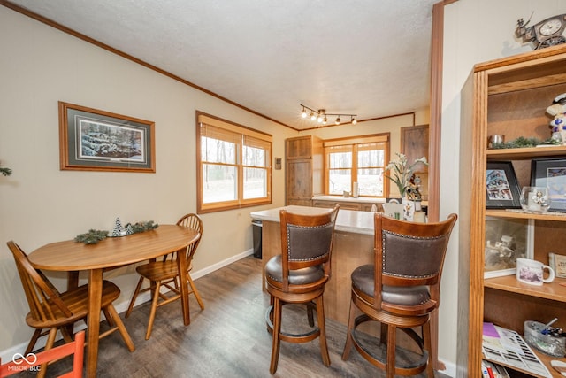 dining space with ornamental molding, dark wood finished floors, and baseboards