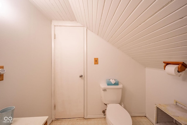 bathroom with baseboards, vaulted ceiling, toilet, and tile patterned floors