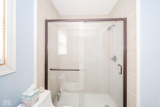 bathroom featuring a stall shower and toilet