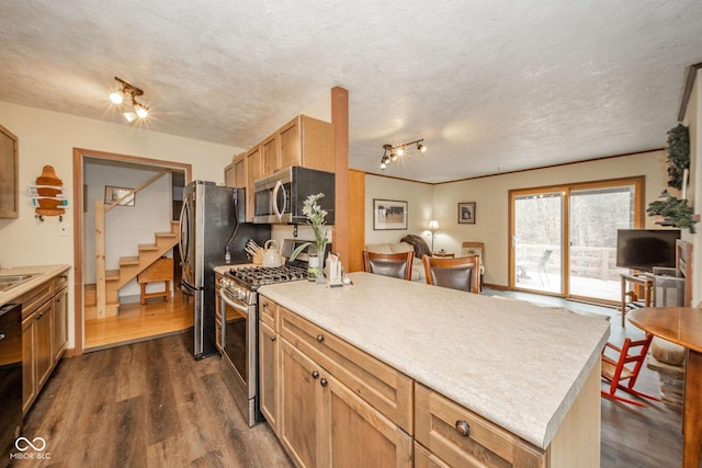 kitchen featuring appliances with stainless steel finishes, dark wood finished floors, a peninsula, and a textured ceiling