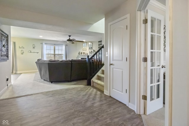 living room with a ceiling fan, stairway, baseboards, and wood finished floors