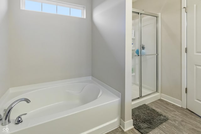 full bathroom featuring a stall shower, a garden tub, and baseboards