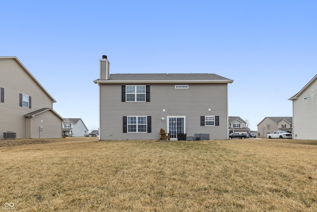 back of property featuring a yard, a chimney, and central air condition unit