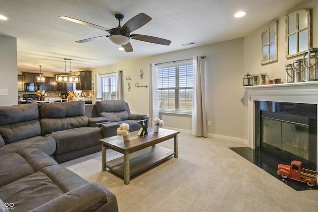 living room with recessed lighting, light colored carpet, visible vents, a fireplace with flush hearth, and baseboards