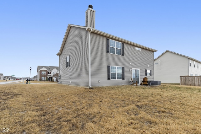 rear view of house featuring central AC, a yard, and a chimney