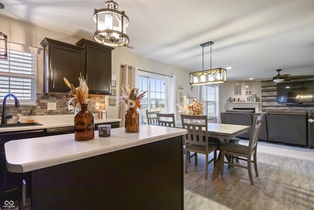 kitchen with dark brown cabinetry, plenty of natural light, a sink, light countertops, and backsplash