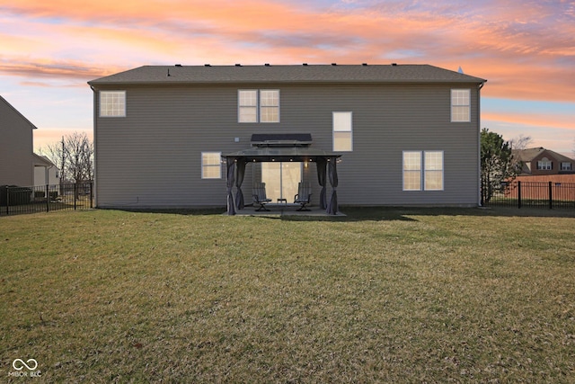 back of property at dusk featuring a patio area, a lawn, and a fenced backyard