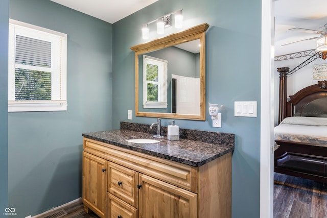 ensuite bathroom featuring connected bathroom, wood finished floors, vanity, baseboards, and a ceiling fan