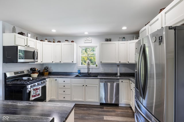 kitchen with dark countertops, dark wood-style floors, appliances with stainless steel finishes, a sink, and recessed lighting