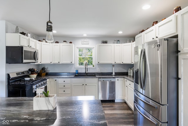 kitchen featuring stainless steel appliances, dark countertops, and a sink