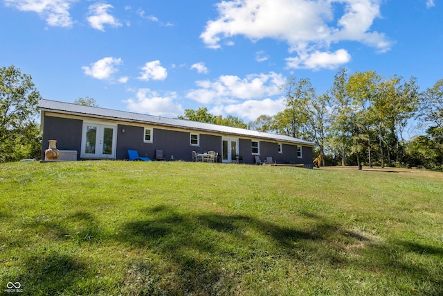 back of property with a yard, metal roof, and french doors