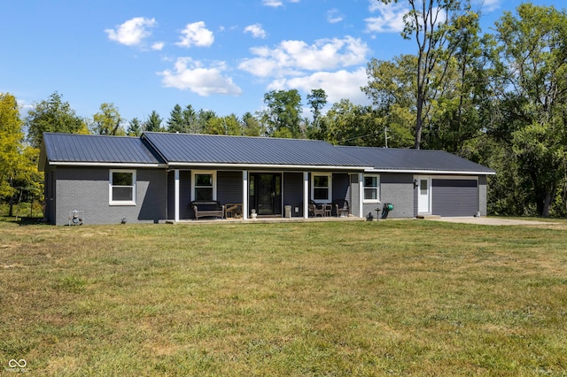 ranch-style house featuring metal roof, an attached garage, brick siding, driveway, and a front lawn