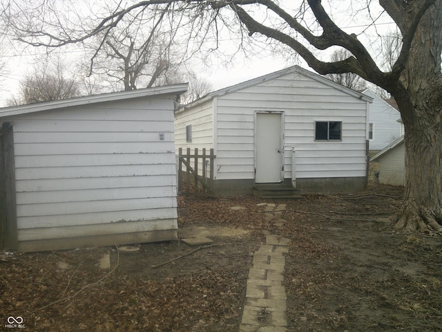 back of house with entry steps, an outdoor structure, and fence