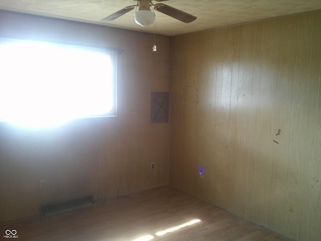 unfurnished room featuring a ceiling fan, visible vents, wood walls, and wood finished floors