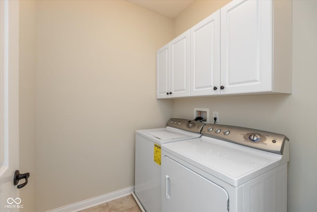 laundry area featuring light tile patterned floors, baseboards, cabinet space, and washer and dryer