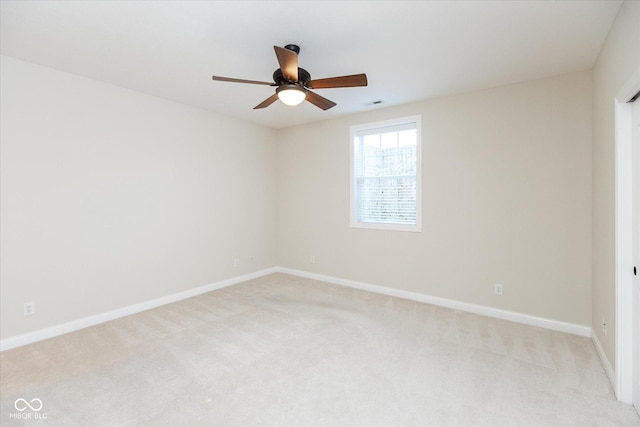 spare room with light carpet, ceiling fan, visible vents, and baseboards