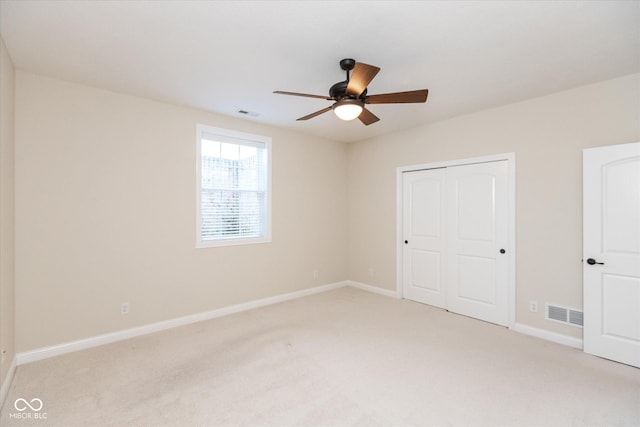 unfurnished bedroom featuring light carpet, visible vents, baseboards, and a closet