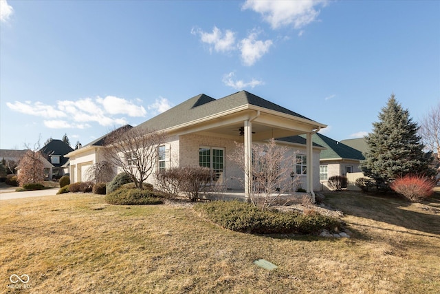 view of property exterior featuring a garage, a lawn, a ceiling fan, and brick siding