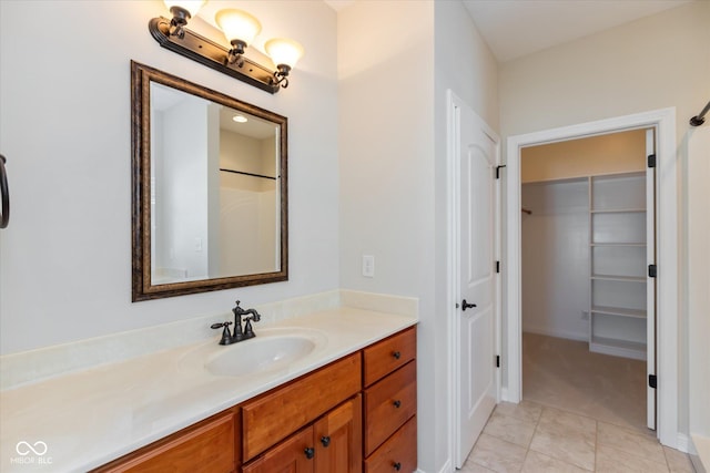 full bathroom with tile patterned flooring, vanity, and a walk in closet