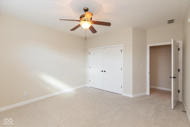 unfurnished bedroom featuring baseboards, visible vents, light colored carpet, ceiling fan, and a closet