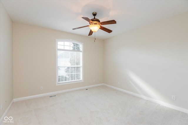 spare room featuring baseboards, ceiling fan, visible vents, and light colored carpet