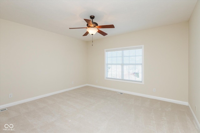 spare room featuring baseboards, a ceiling fan, visible vents, and light colored carpet