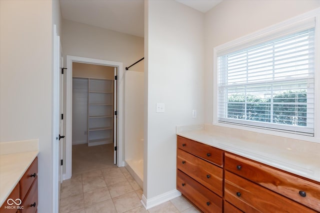 full bathroom featuring baseboards, a shower, tile patterned floors, a walk in closet, and vanity