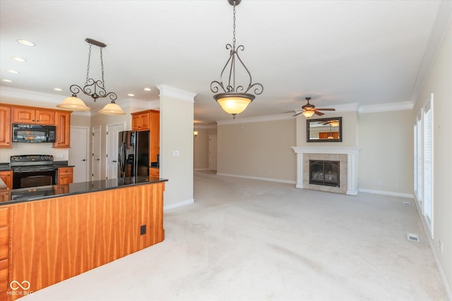 kitchen with visible vents, a tile fireplace, dark countertops, ornamental molding, and black appliances